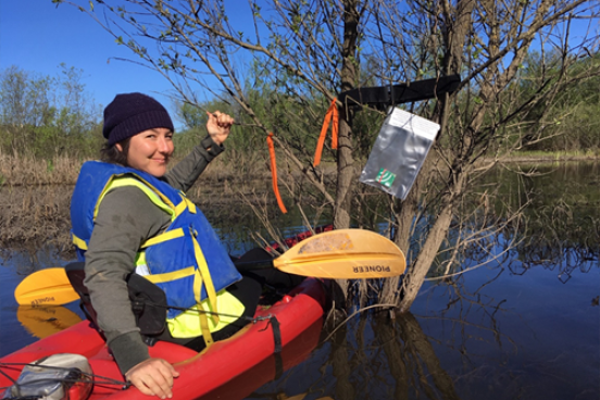 Student in kayak in a wetland with audio recorder in view