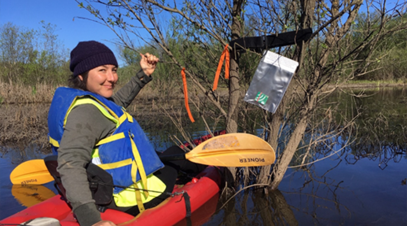 Student in kayak in a wetland with audio recorder in view
