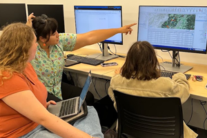 Three students analyzing computer map