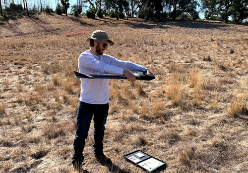 Student in field holding a drone