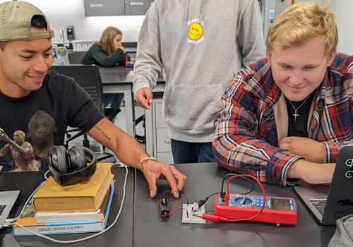 Two students examining an electrical device