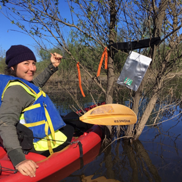Student in kayak in a wetland with audio recorder in view