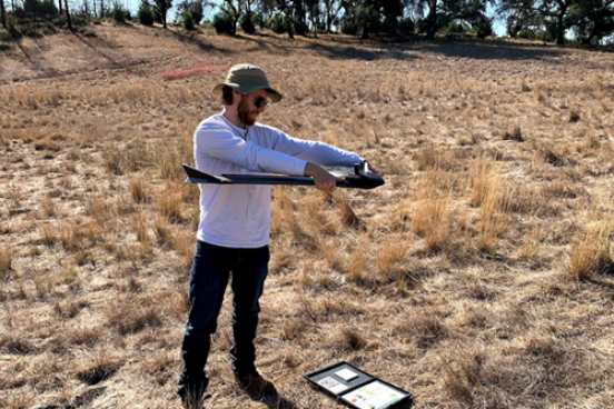 Student in field holding a drone