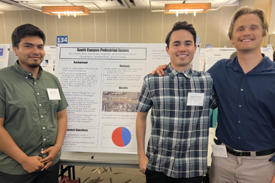 Three students in front of poster in reserach colloquium