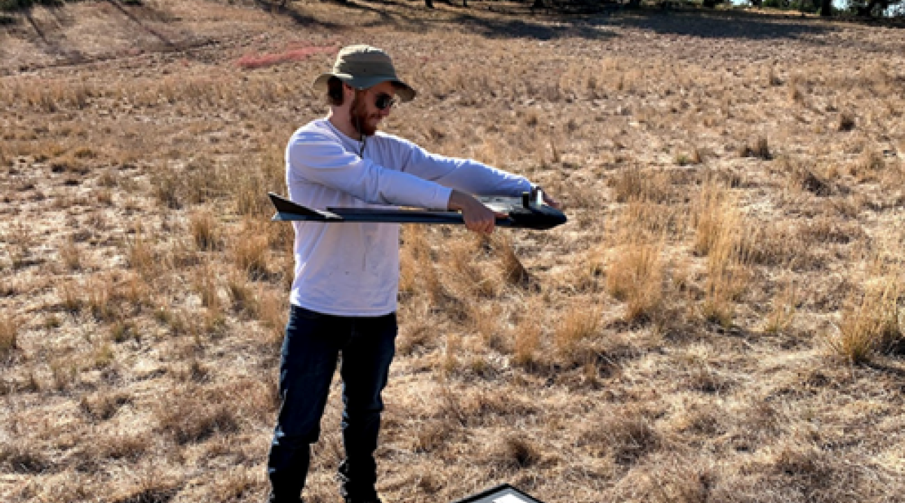 Student in field holding a drone