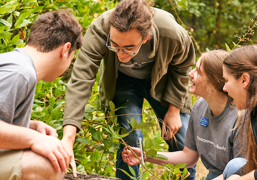 Student teacher pointing to a log while explaining an ecological concept