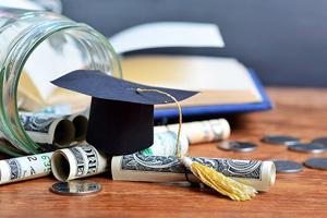 graduation hat and rolls of money on a table