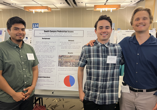 Three students in front of poster in reserach colloquium